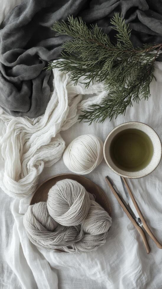 Cozy crafting setup with green yarn, a steaming drink, and natural decorations on a wooden table photo
