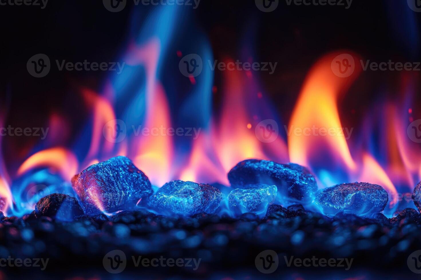 Vibrant flames heating glowing blue crystals on black pebbles photo