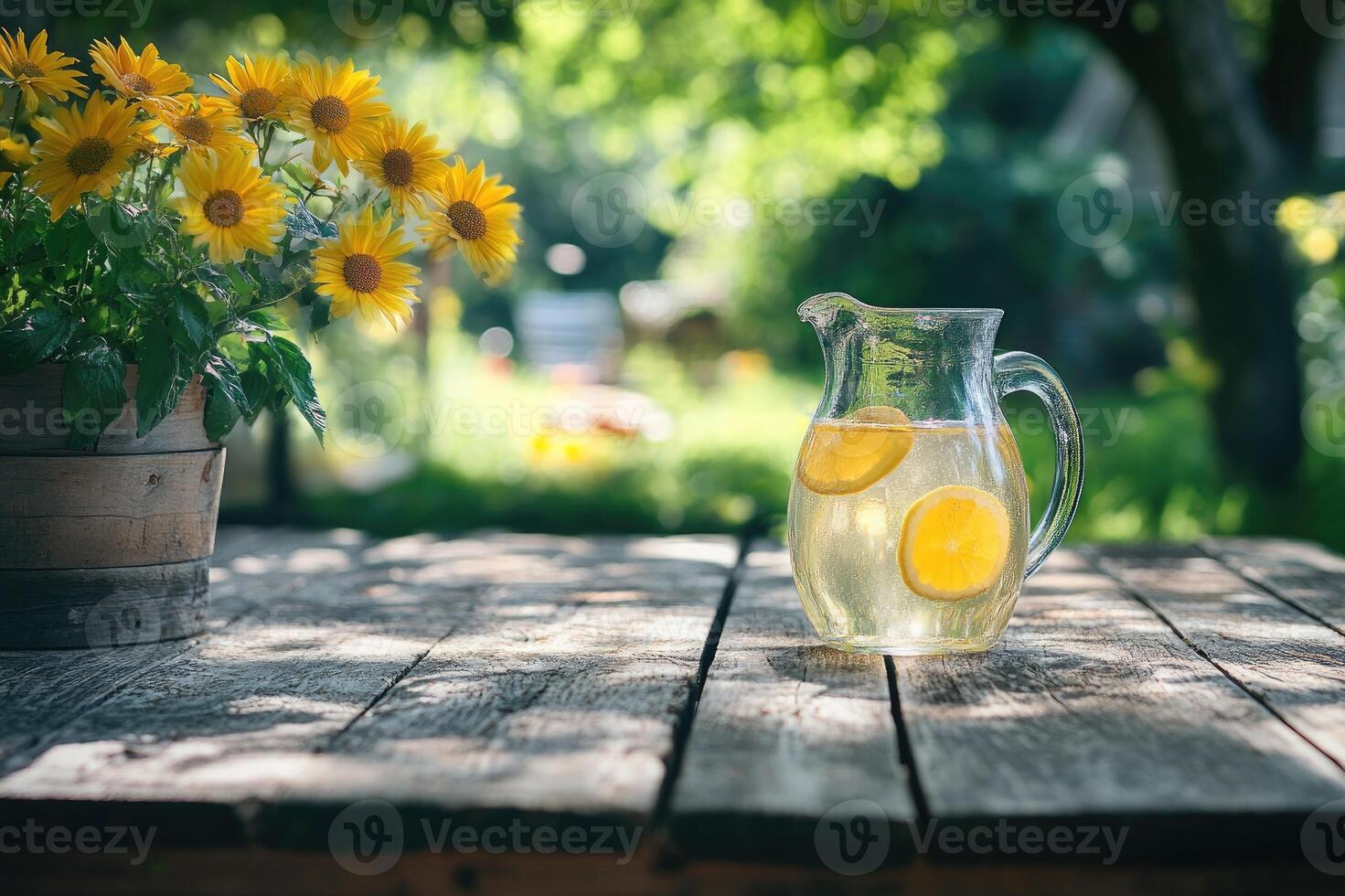 Refreshing lemonade in glass pitcher on rustic wooden table in blooming summer garden photo