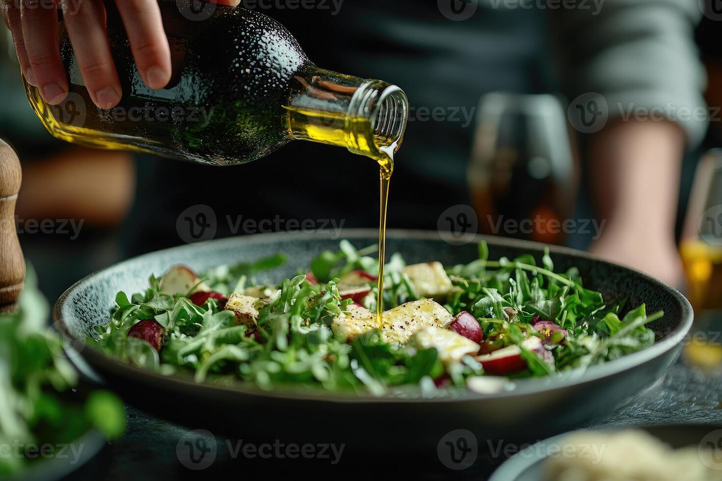 Chef pouring olive oil over fresh arugula salad with grilled halloumi and radish photo