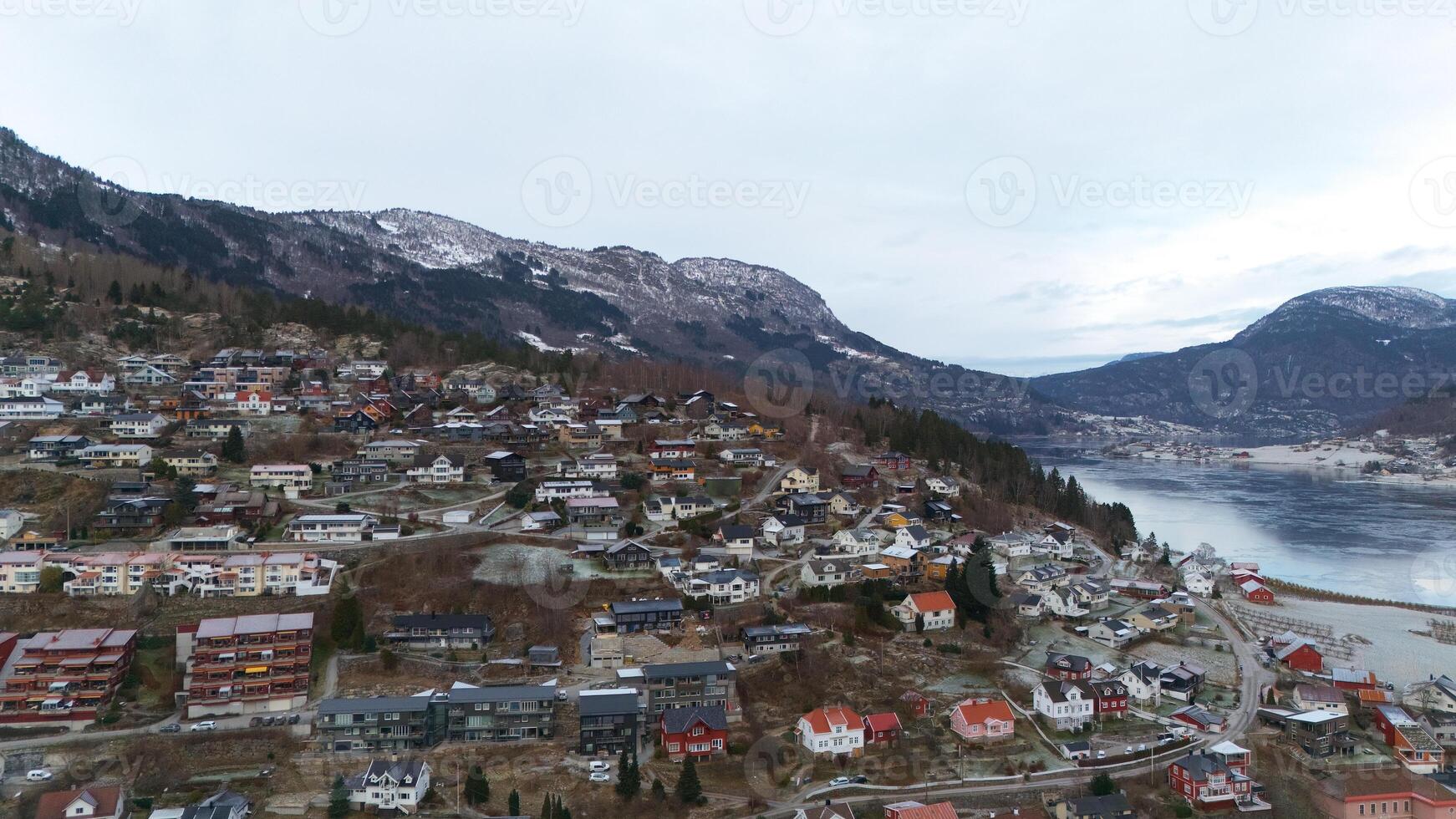 Picturesque Hillside Town in Norway Overlooking a Serene Fjord and Snowy Peaks photo