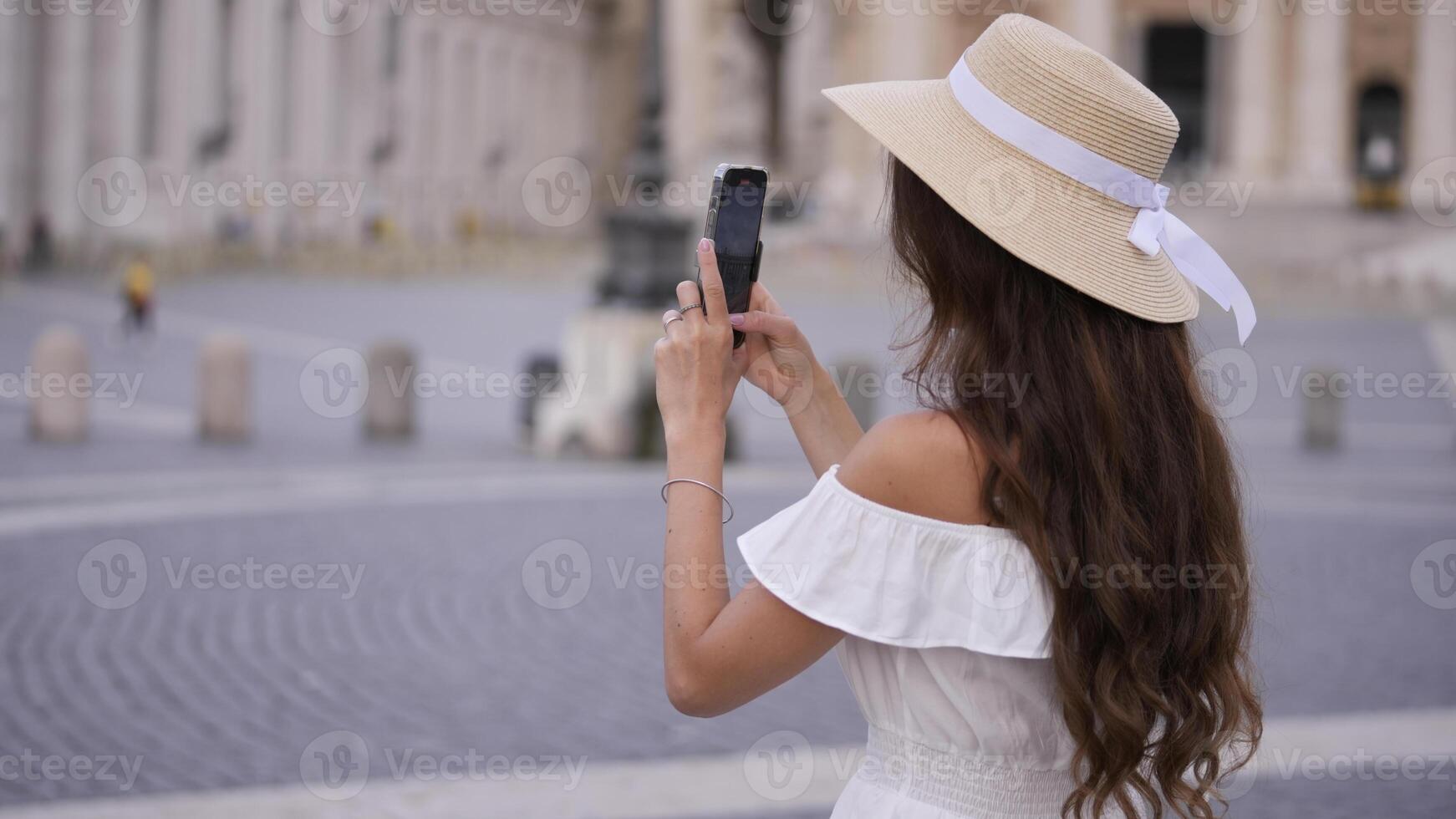 Tourist in White Dress Capturing St. Peters Square on Phone photo