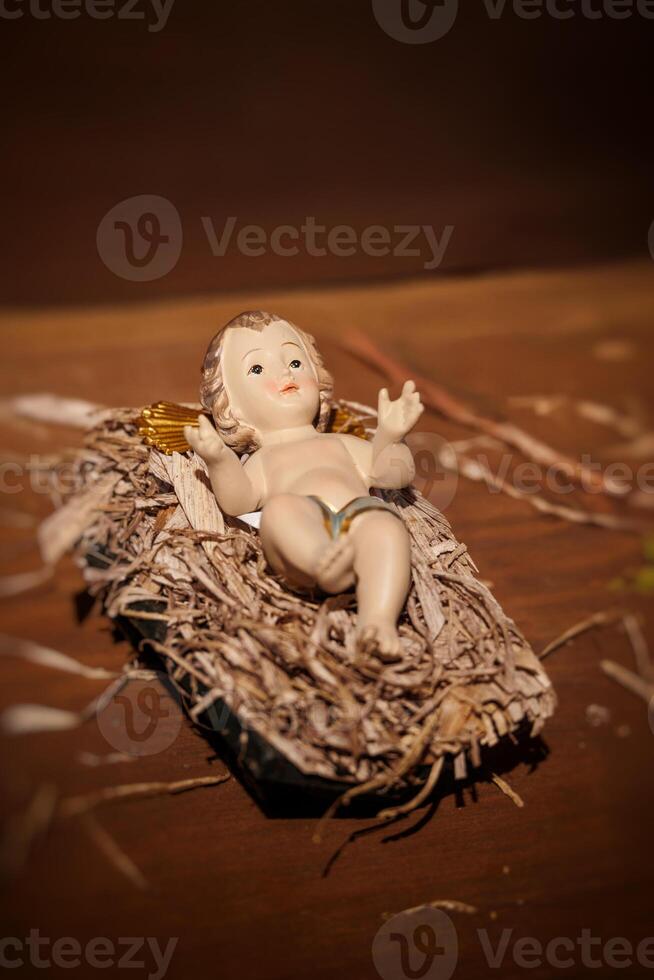A small baby jezus figurine with golden wings rests on a bed of straw photo