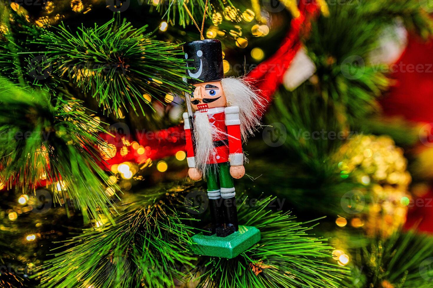 A festive nutcracker ornament hangs on a decorated Christmas tree, photo