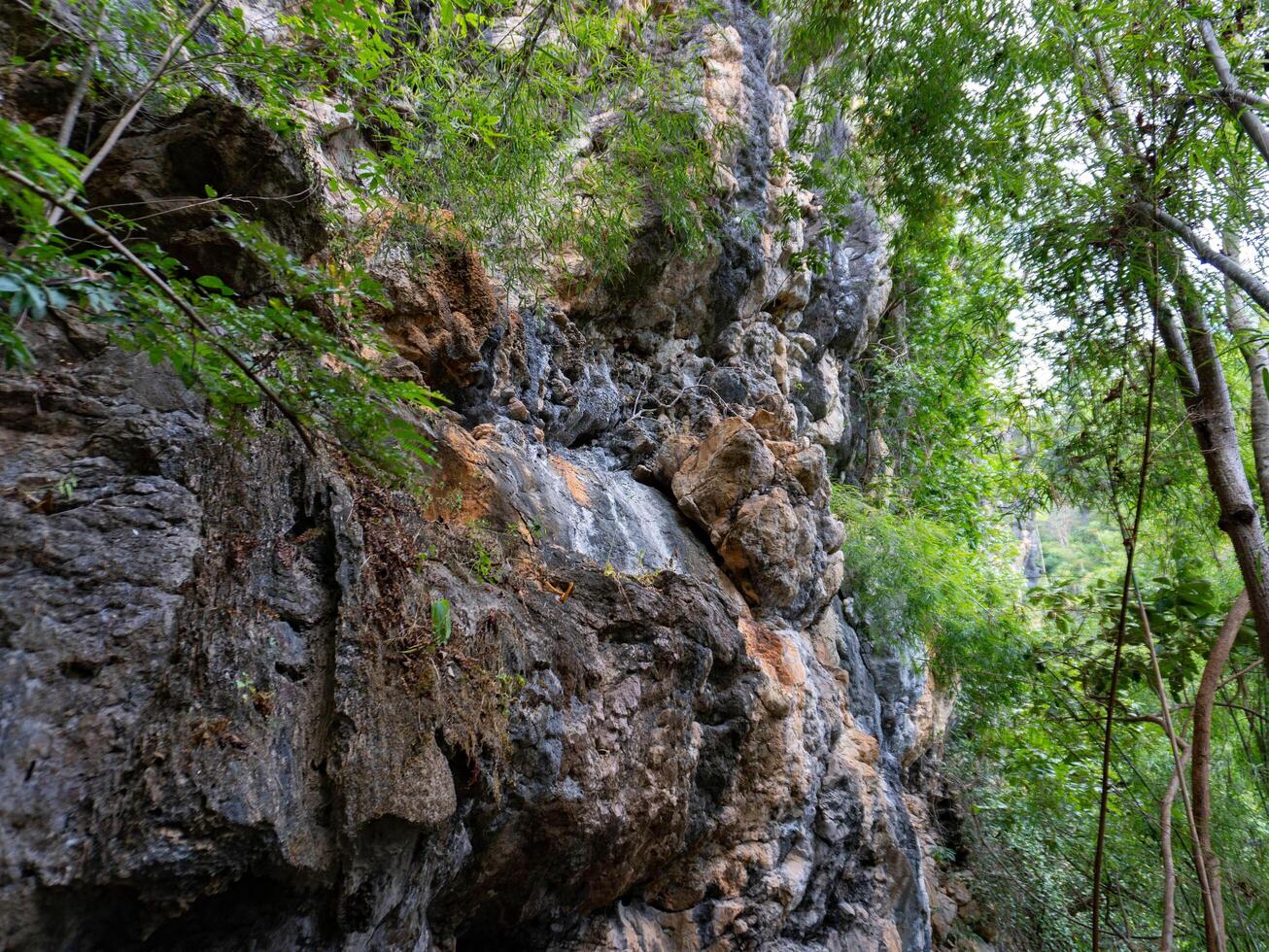 Amazing hillside cliff with compressed layer rock structure of volcanic rock. Close-up texture of volcanic rock. Cracked broken crumbled. photo