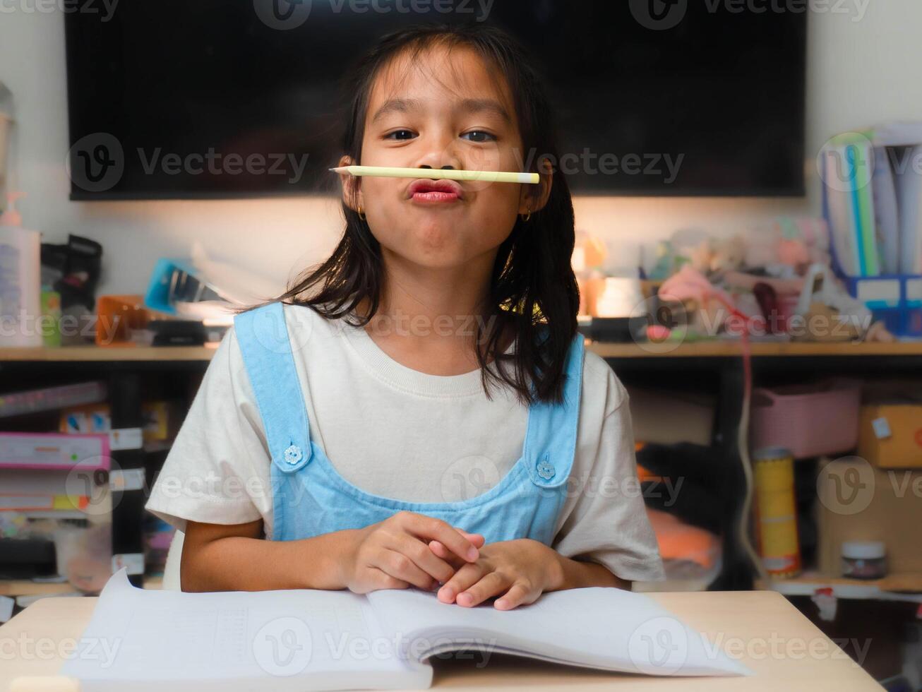 Homeschool Asian little young girl student learning attentively, reading and studying with pencil in hand and learning. photo