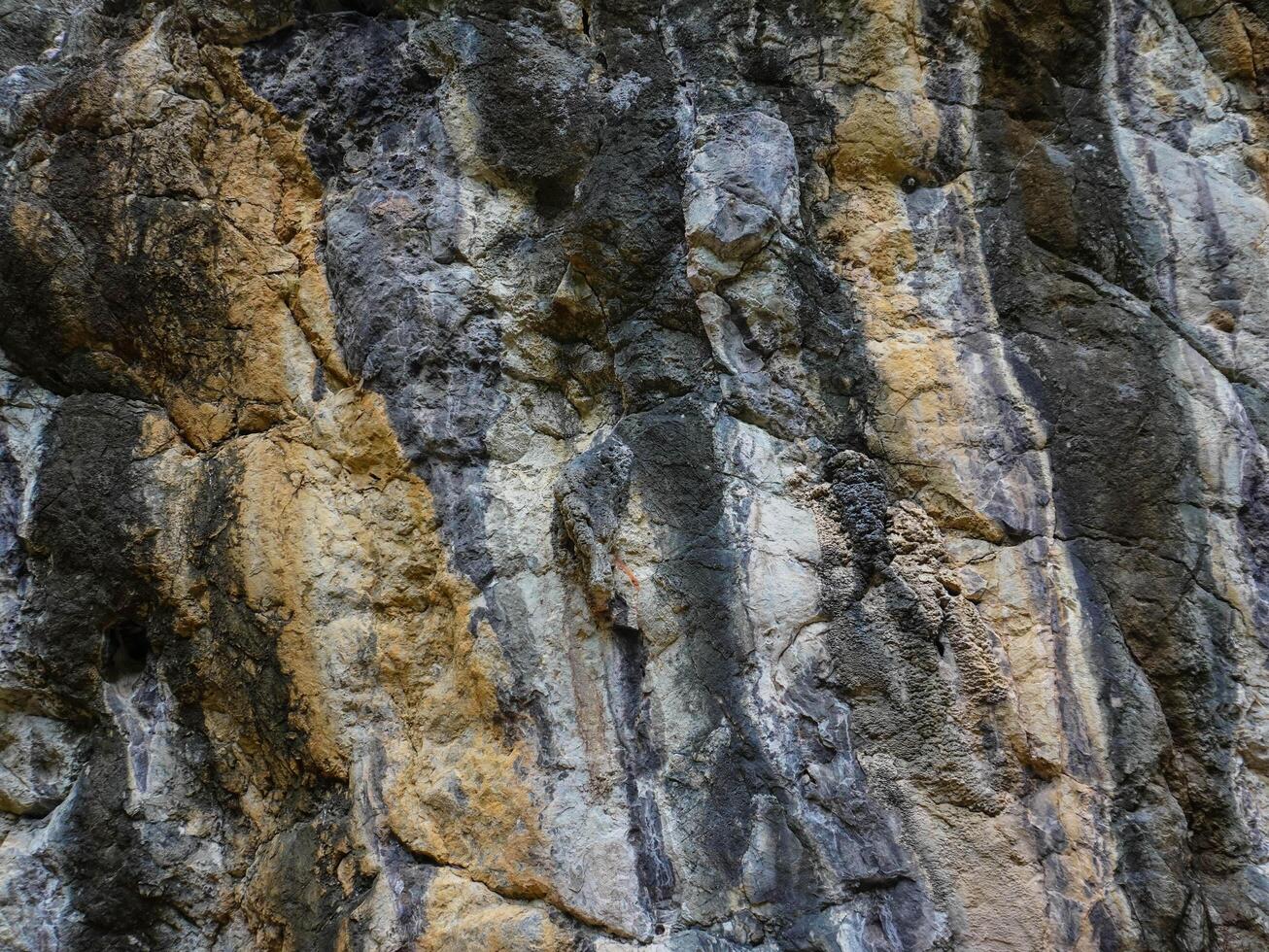 Amazing hillside cliff with compressed layer rock structure of volcanic rock. Close-up texture of volcanic rock. Cracked broken crumbled. photo