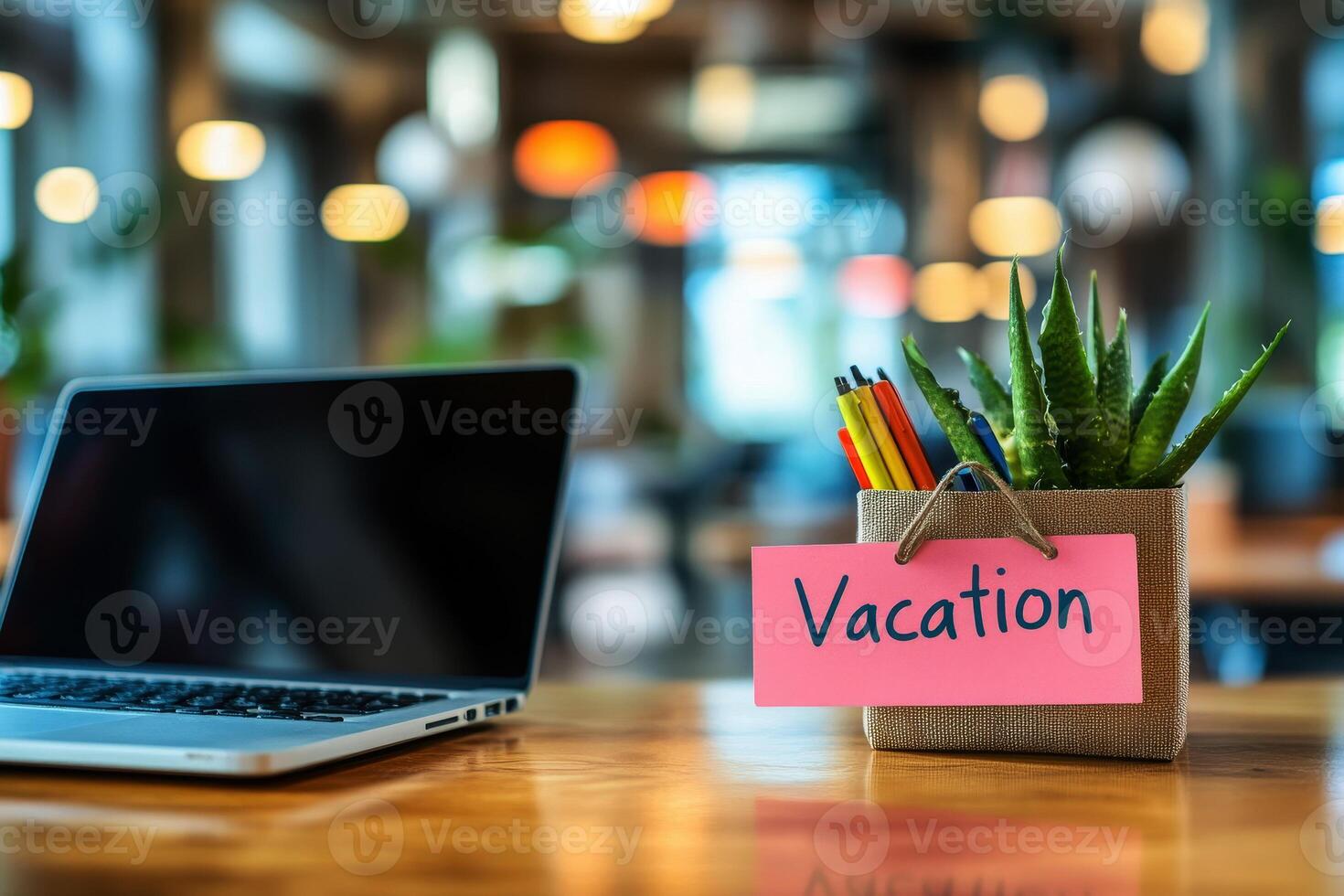 Office table with the message Vacation or holidays written on a note. Laptop and office supplies on blurred background. Out of the office. photo