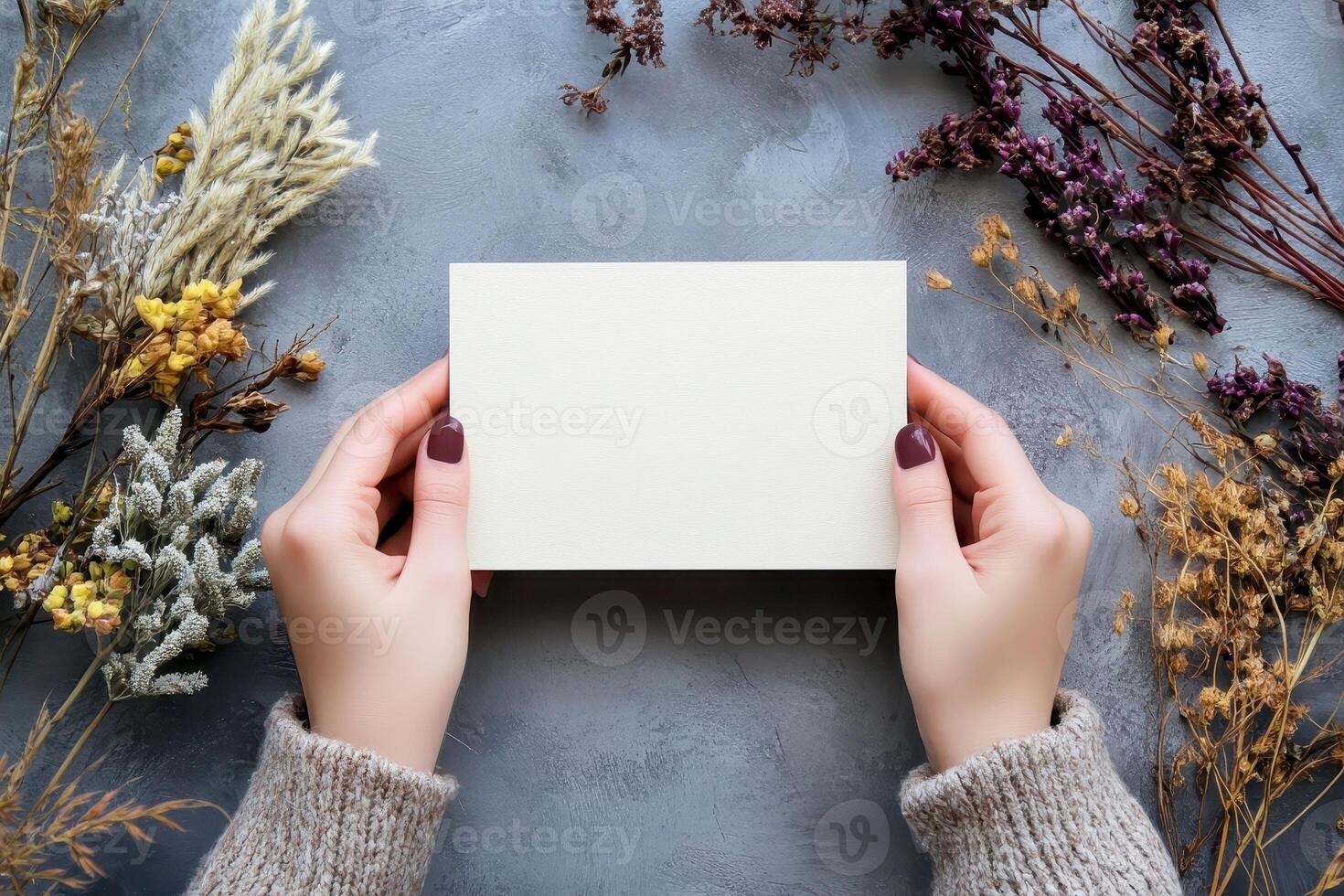Hand holding printed greeting card mock up, blank empty postcard isolated on natural flower background photo