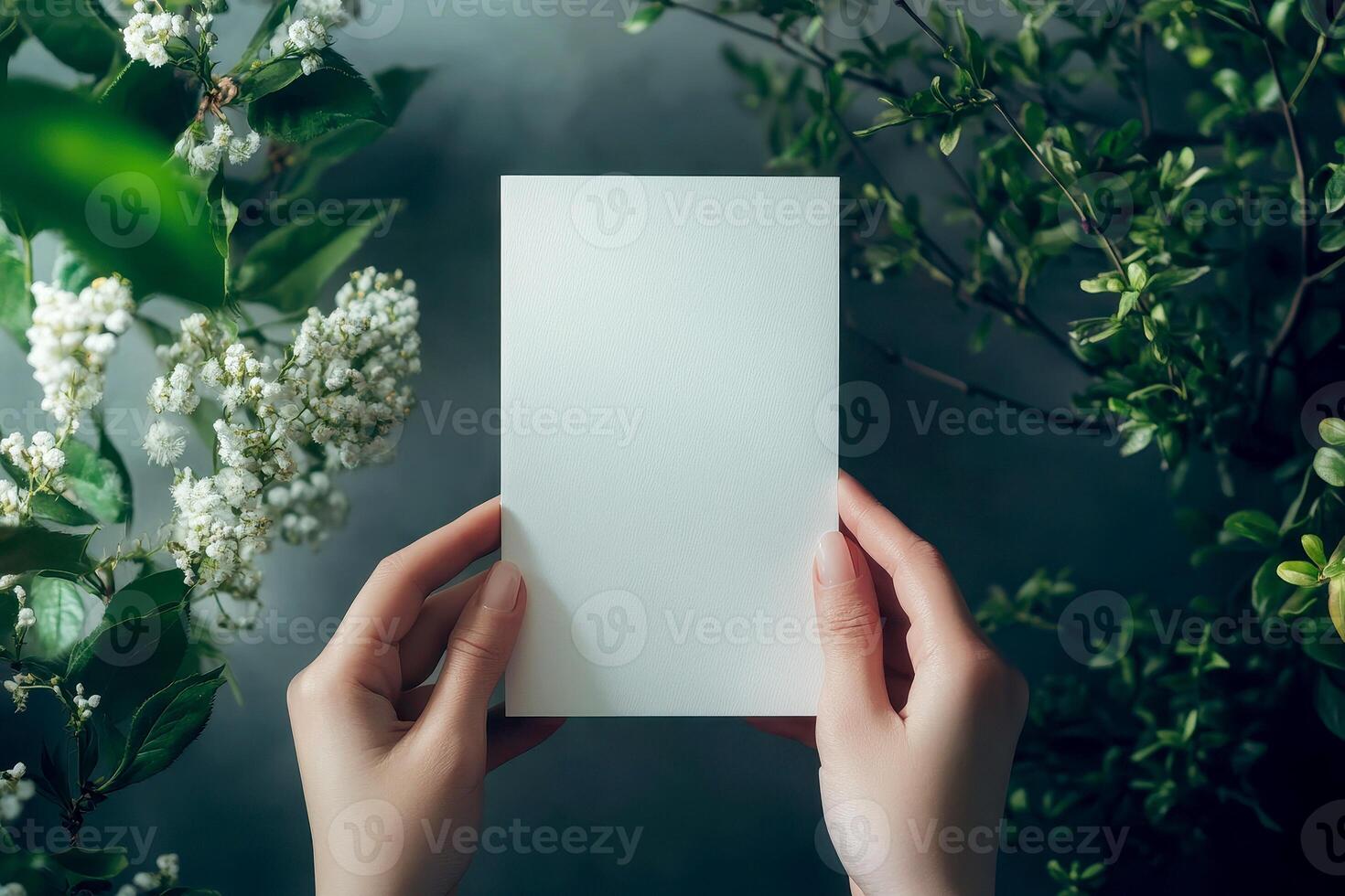 Hand holding printed greeting card mock up, blank empty postcard isolated on natural flower background photo