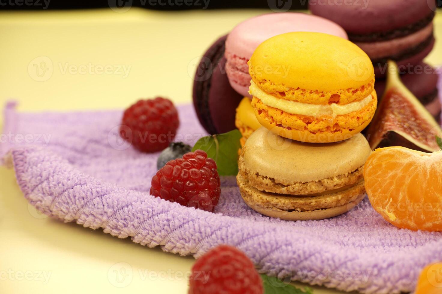 Assortment of macaroons and fruits on purple cloth photo