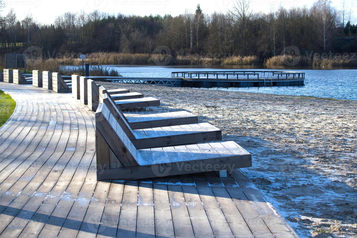 Serene Lakeside View with Wooden Benches and Sandy Beach photo