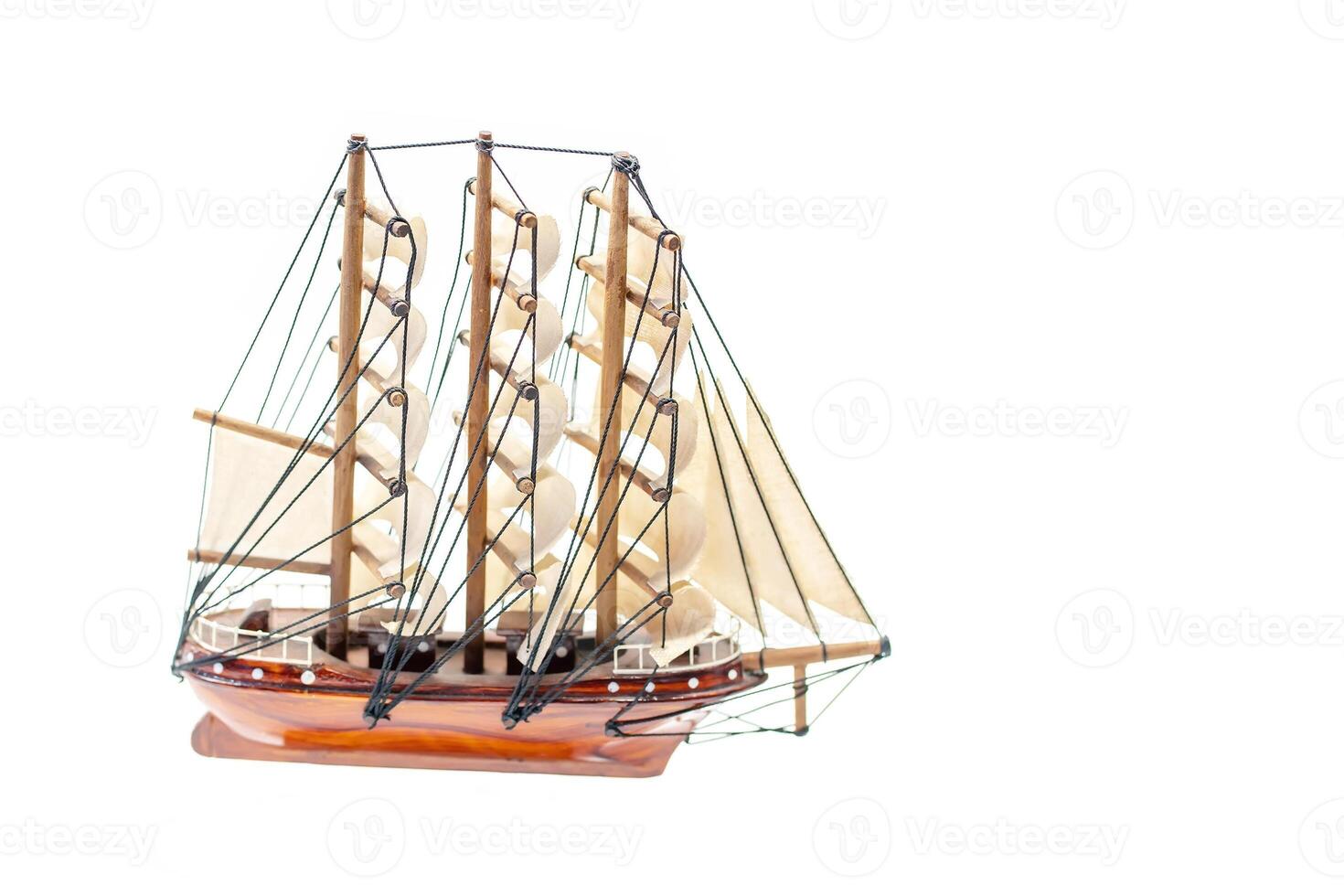 Detailed miniature of a classic sailing ship, showcasing intricate rigging and sails, set against a white background. photo