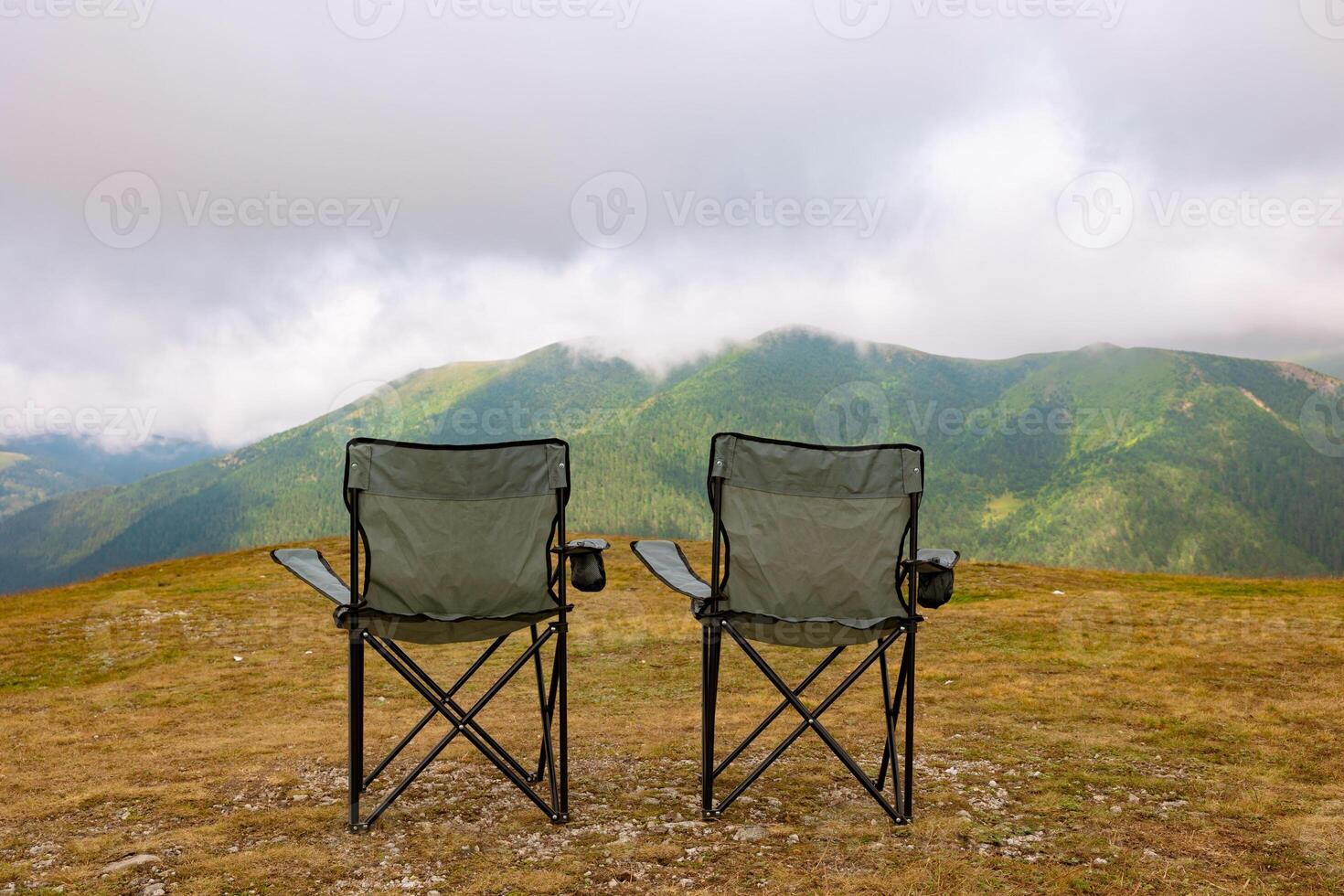 Two camping charis on the hills and misty mountains on the background photo