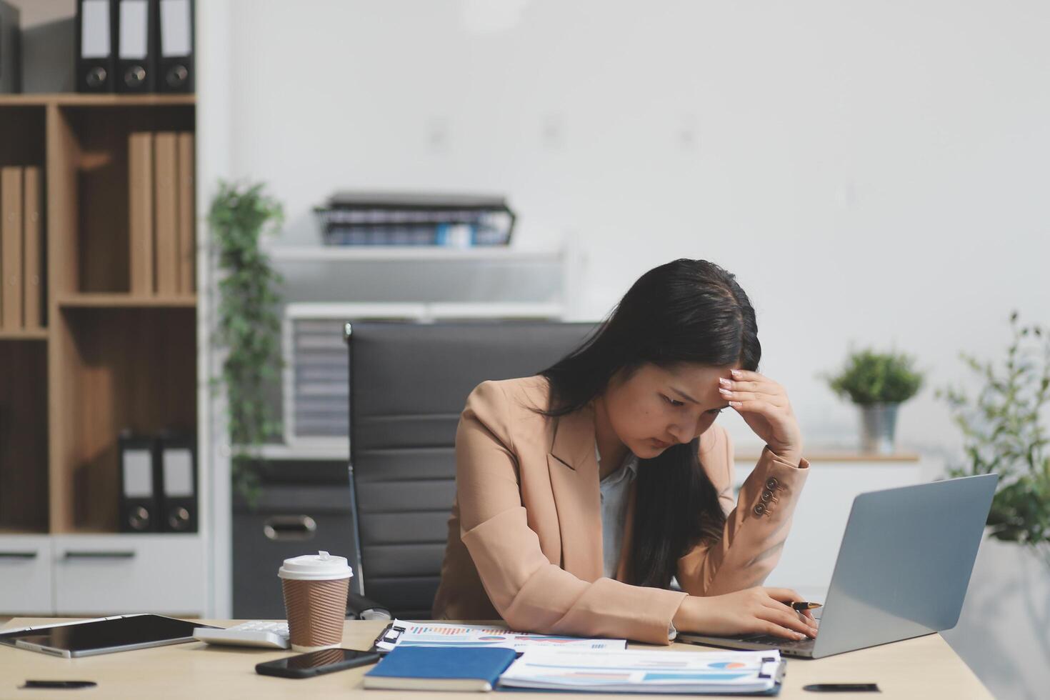 Portrait of tired young business Asian woman work with documents tax laptop computer in office. Sad, unhappy, Worried, Depression, or employee life stress concept photo