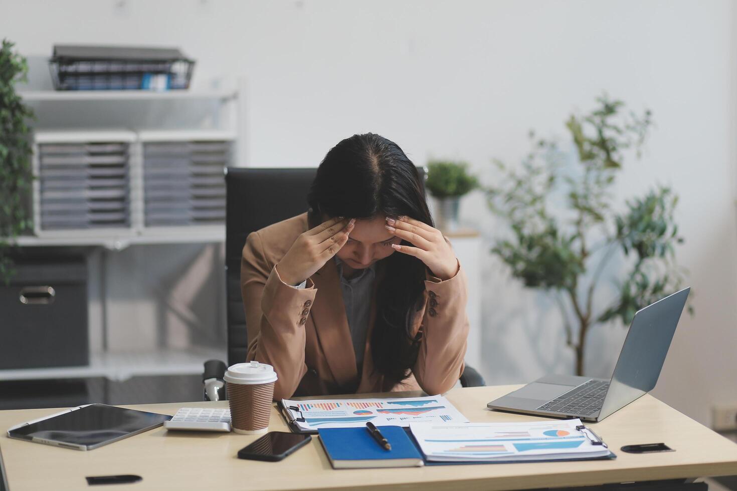 Portrait of tired young business Asian woman work with documents tax laptop computer in office. Sad, unhappy, Worried, Depression, or employee life stress concept photo