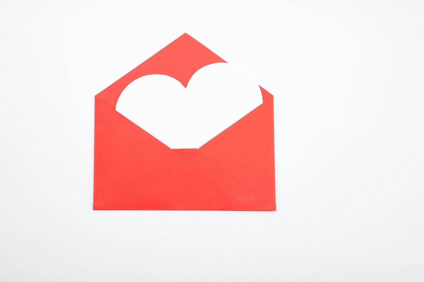 Open red envelope made of origami paper from which a white heart flies out. photo
