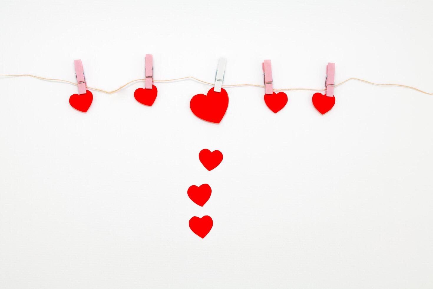 Red hearts with clothespins hanging on clothesline isolated on white background. photo
