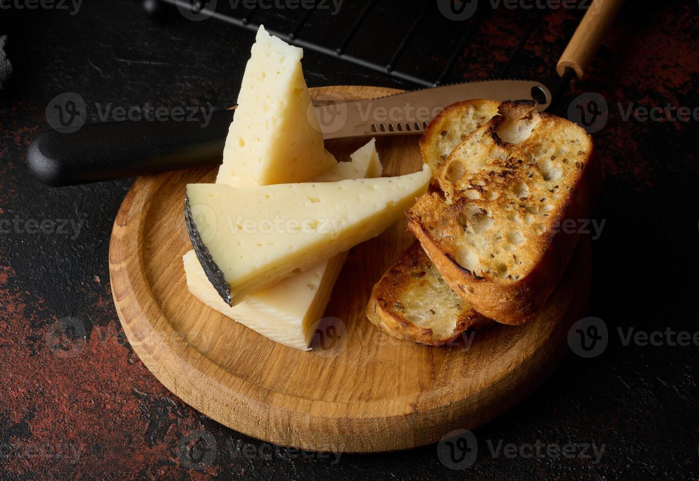Triangular pieces of cheese and fried ciabatta slices on a wooden board photo