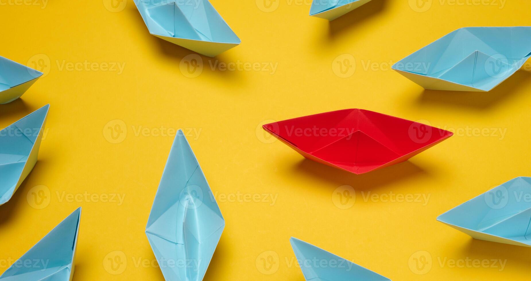 A group of blue paper boats surrounded one red boat, the concept of bullying, search for compromise. photo