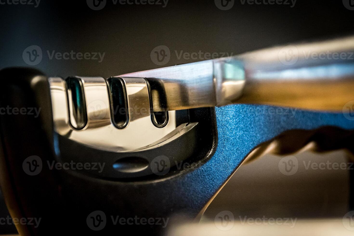 Close-up and detail of a knife in a knife sharpener kitchen tool. photo