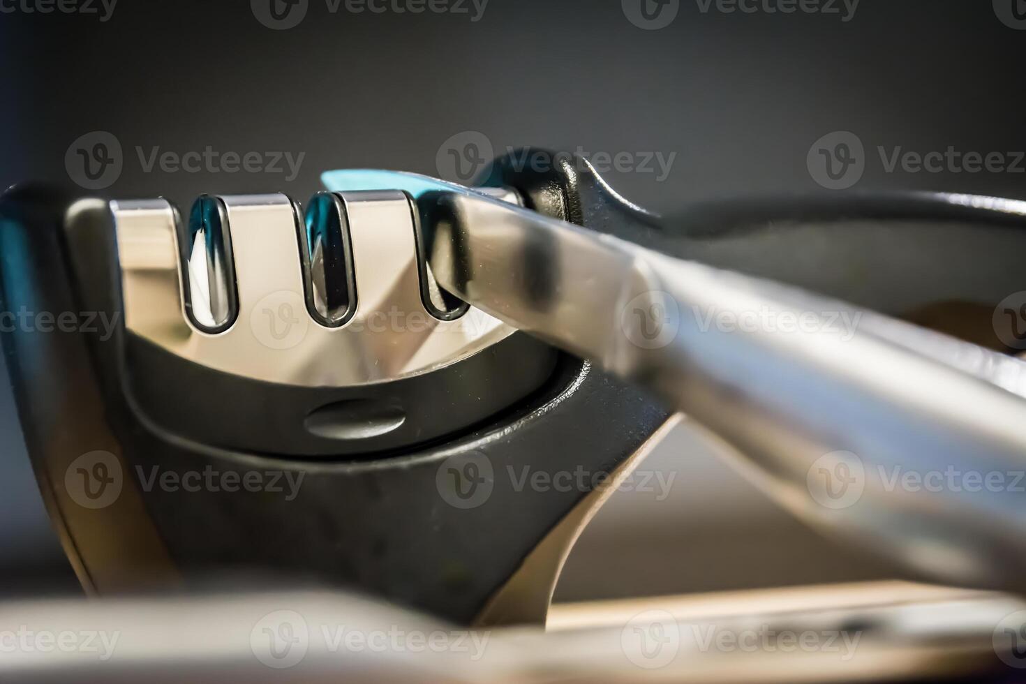Close-up and detail of a knife in a knife sharpener kitchen tool. photo
