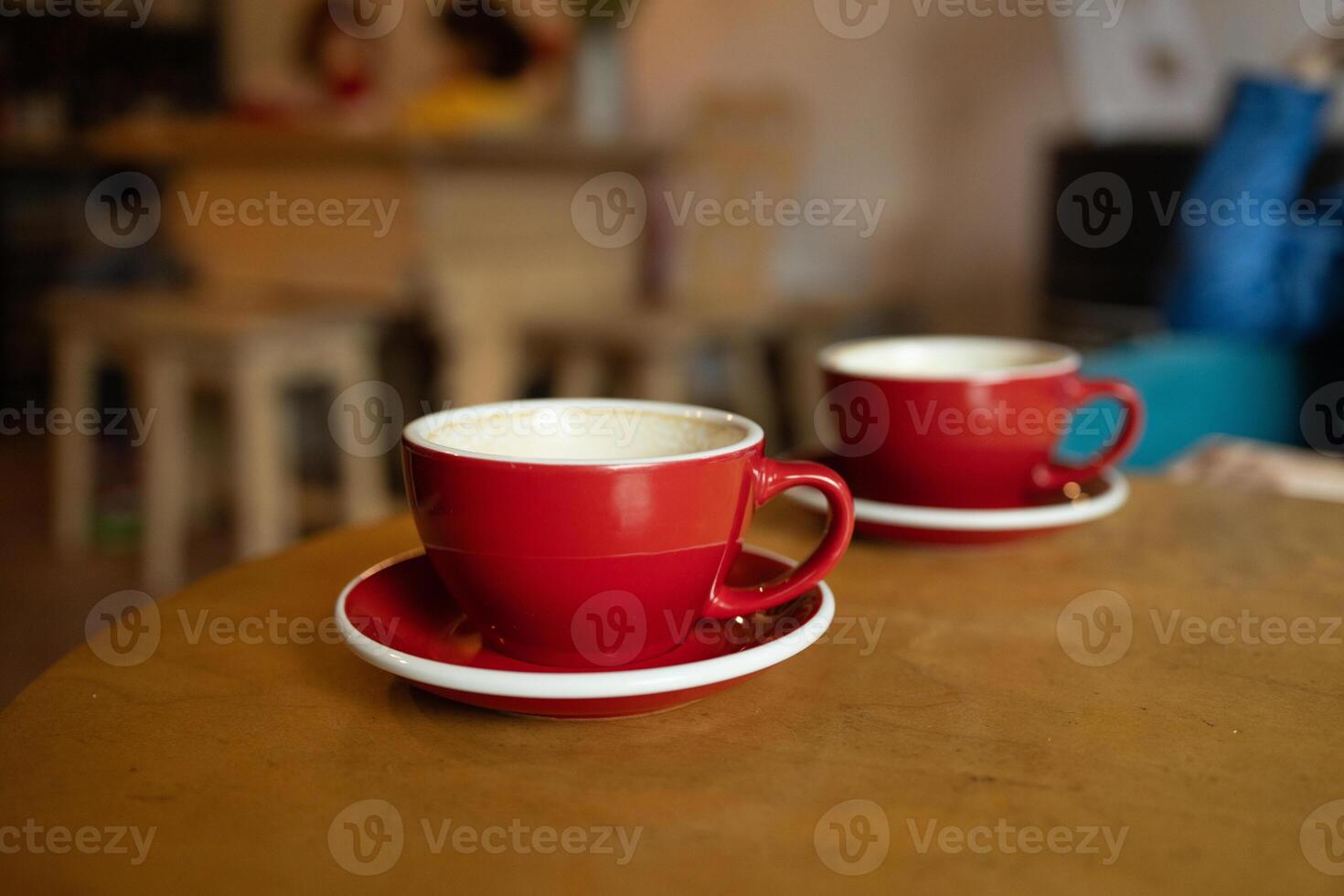 Two red cups of coffee with milk with trendy heart shape latte art. Drinking coffee on the terrace. photo