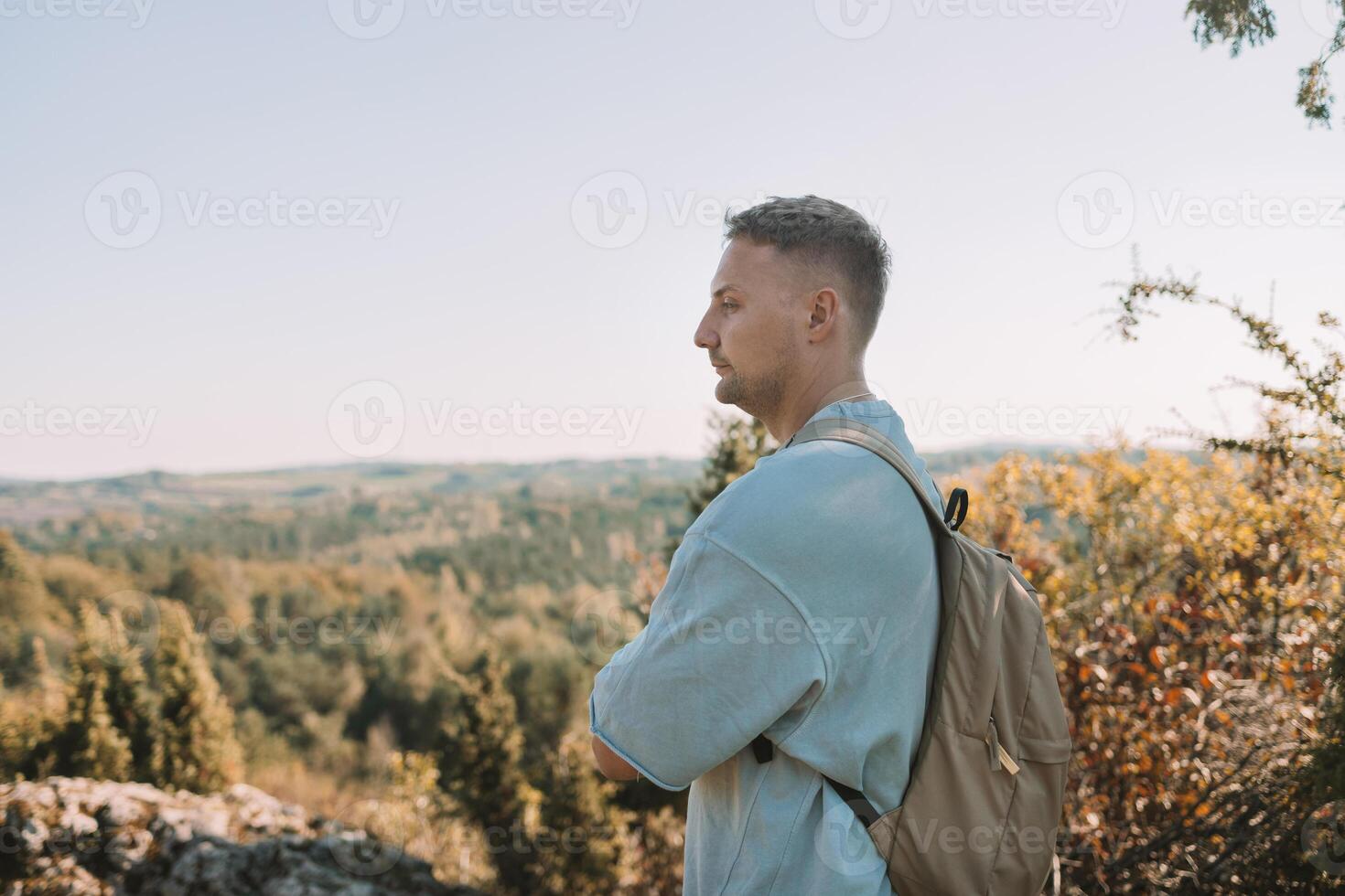 Young happy man hiking in the mountains. A man with a backpack on a hill. photo