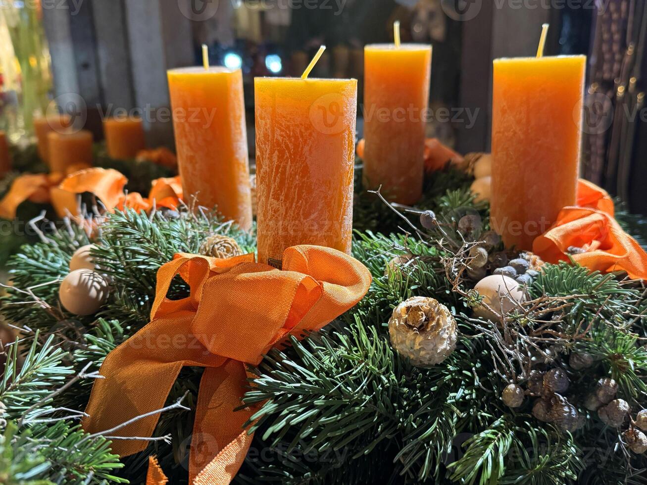 Orange candles on festive wreath with greenery and ornaments photo