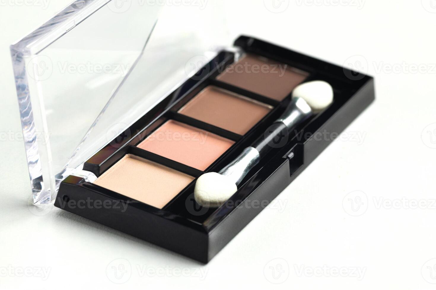A palette of beige, brown warm eyeshadow with an applicator on a white background photo