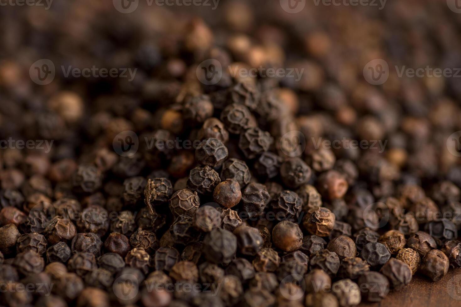 Close up of black pepper or peppercorns as background on wooden background. photo
