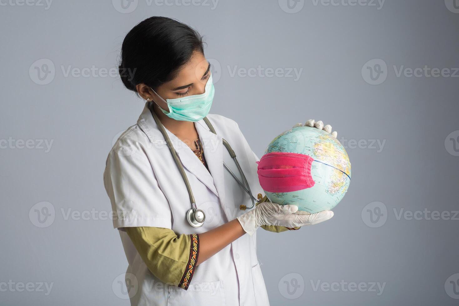 Woman doctor holding world globe with a medicine face mask. World epidemic of coronavirus concept. photo
