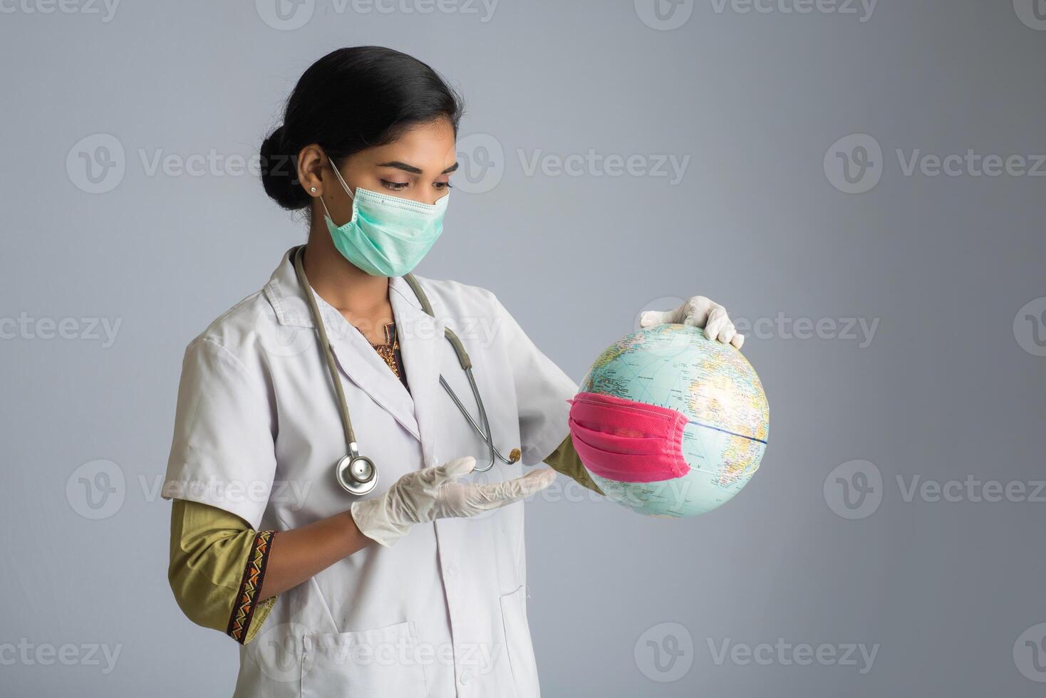 Woman doctor holding world globe with a medicine face mask. World epidemic of coronavirus concept. photo