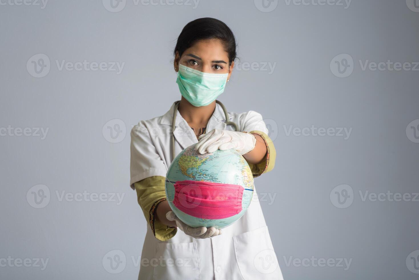 Woman doctor holding world globe with a medicine face mask. World epidemic of coronavirus concept. photo