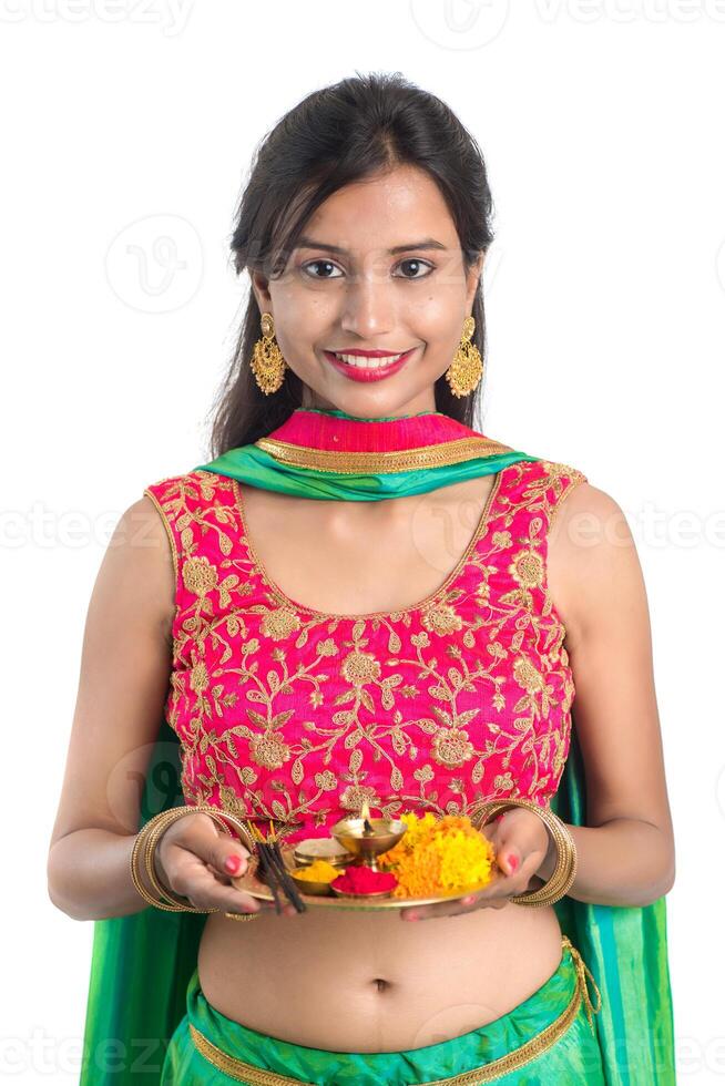 Beautiful Indian young girl holding pooja thali or performing worship on a white background photo