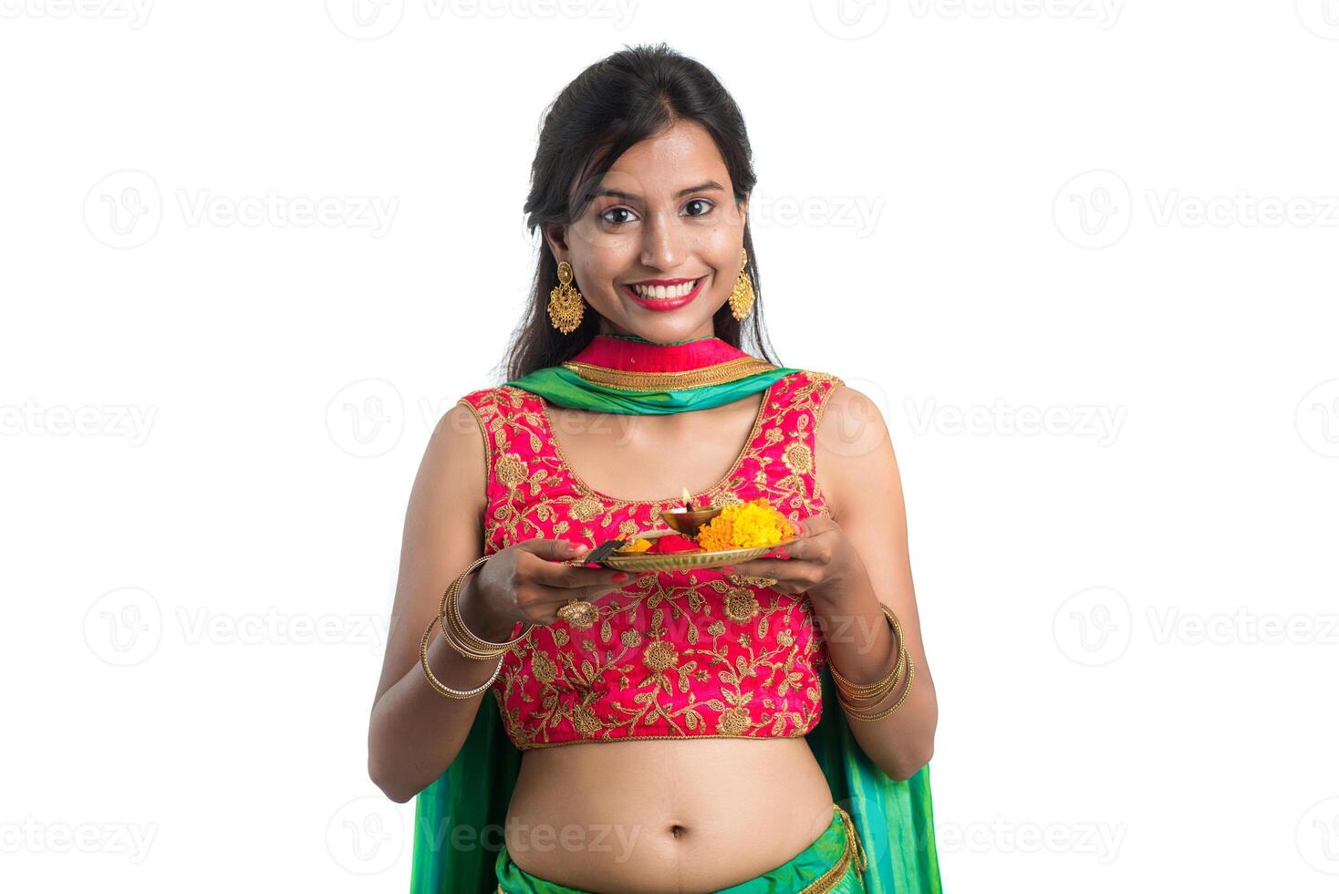 Beautiful Indian young girl holding pooja thali or performing worship on a white background photo