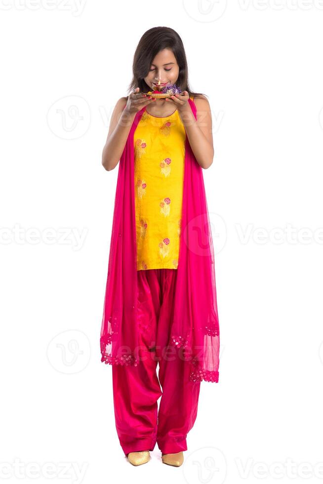 Beautiful Indian young girl holding pooja thali or performing worship on a white background photo
