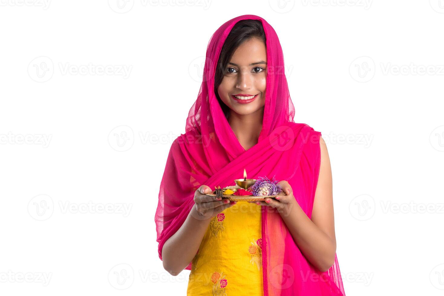 Beautiful Indian young girl holding pooja thali or performing worship on a white background photo