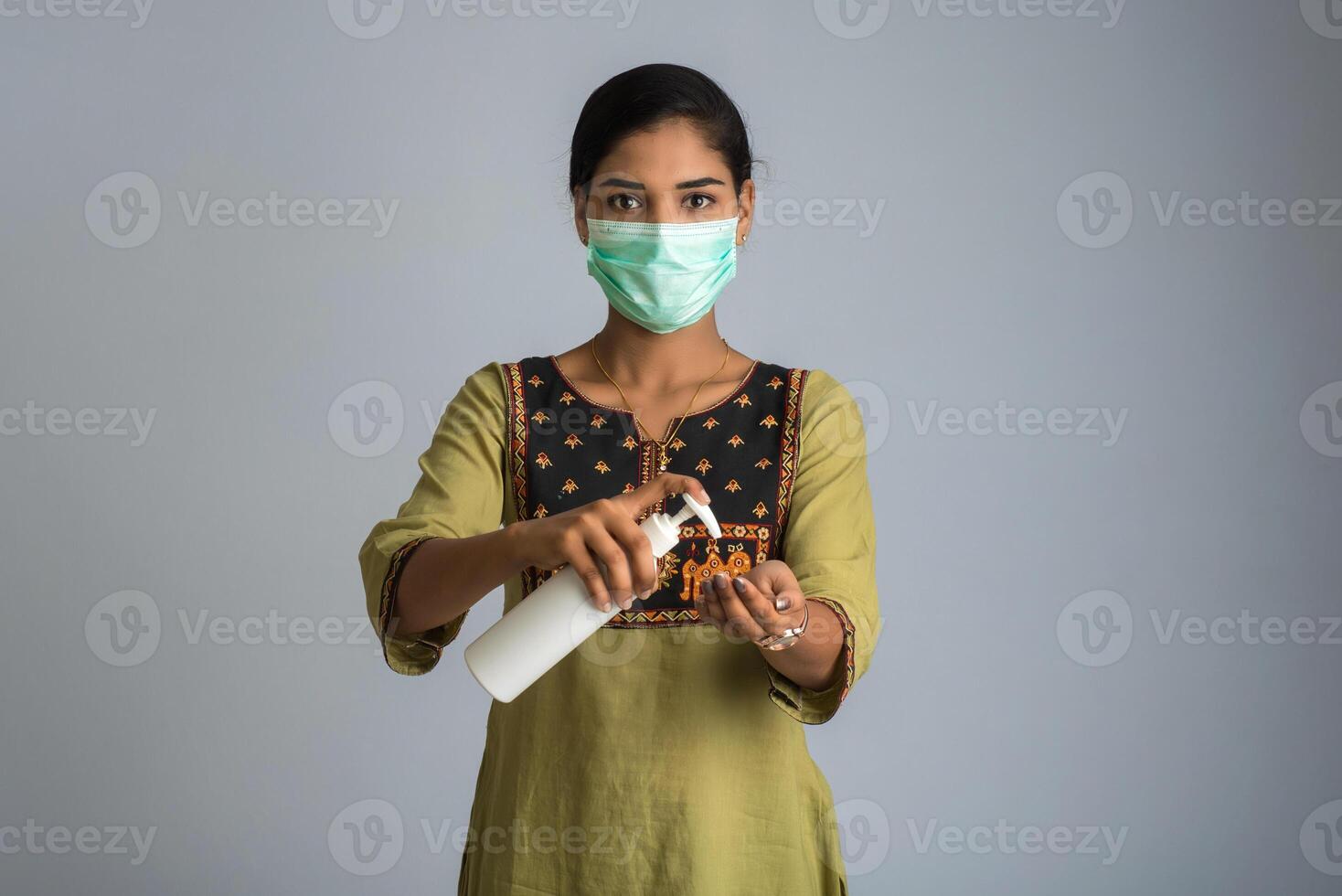 Portrait of young girl using or showing a sanitizing gel from a bottle for hands cleaning. photo