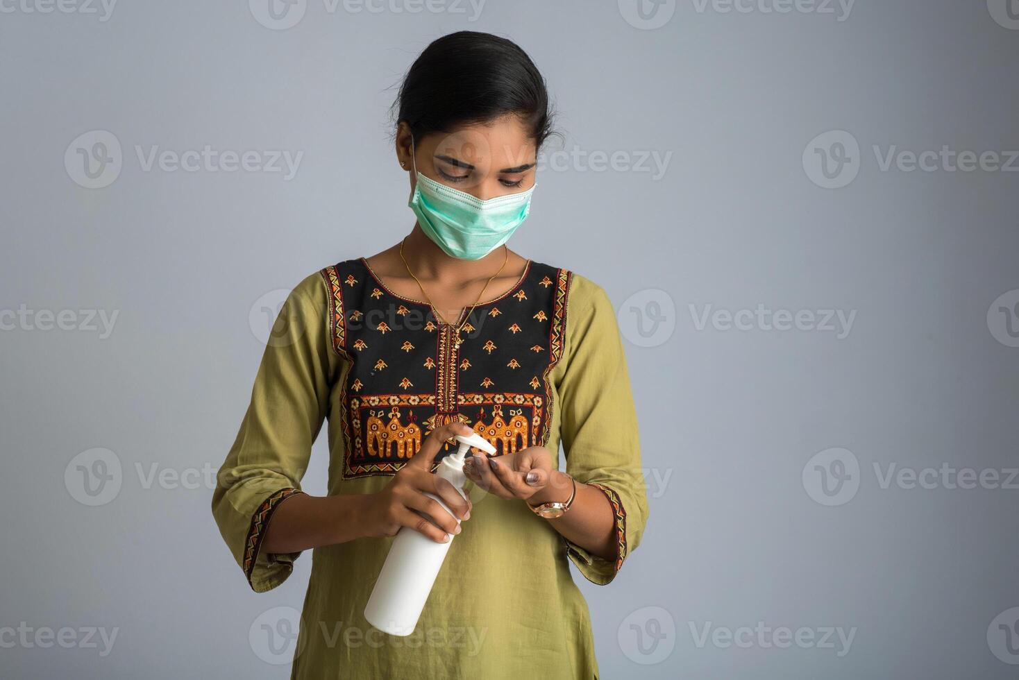 Portrait of young girl using or showing a sanitizing gel from a bottle for hands cleaning. photo
