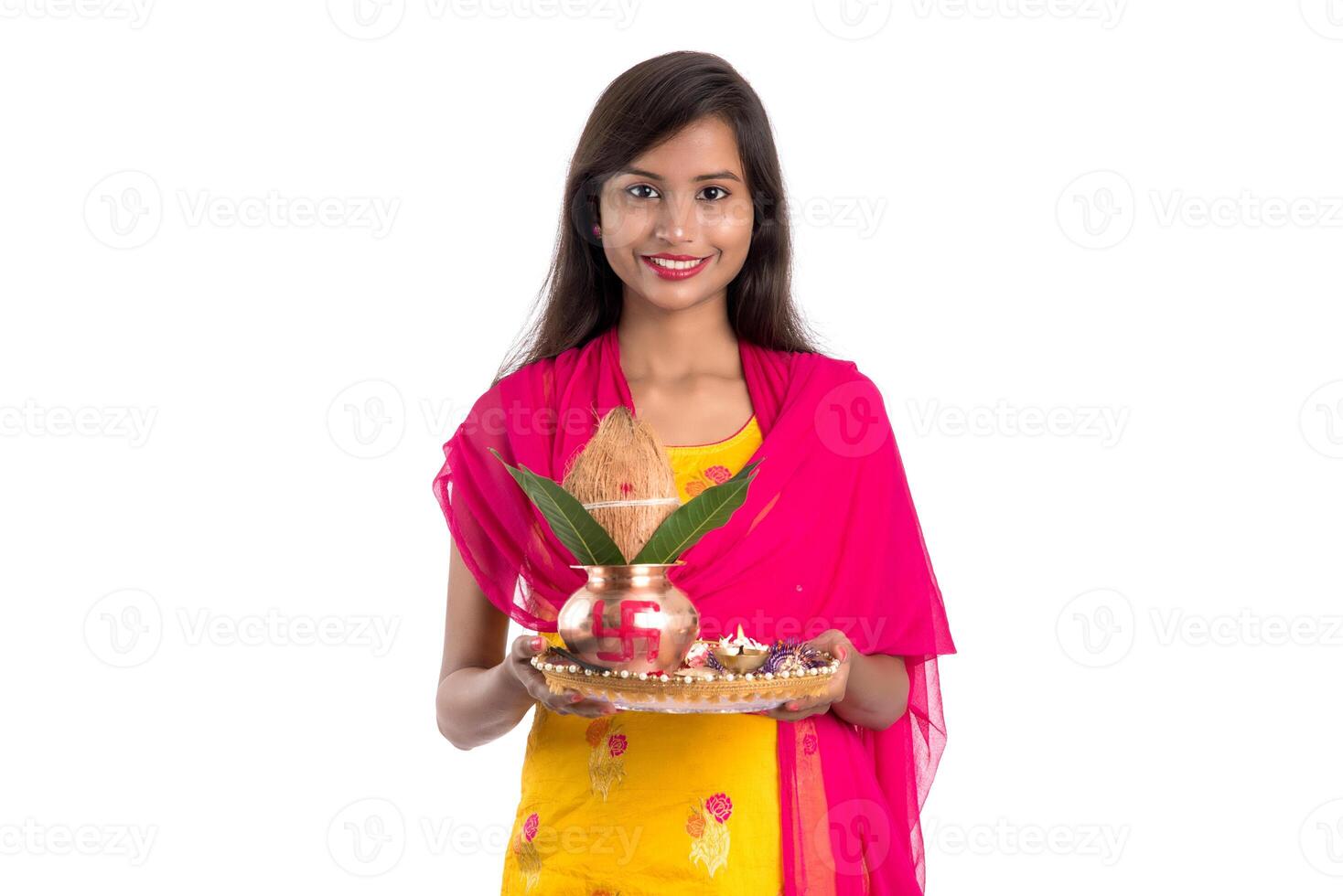 Indian girl holding a traditional copper Kalash with Pooja Thali, Indian Festival, copper Kalash with coconut and mango leaf with floral decoration, essential in Hindu Pooja. photo