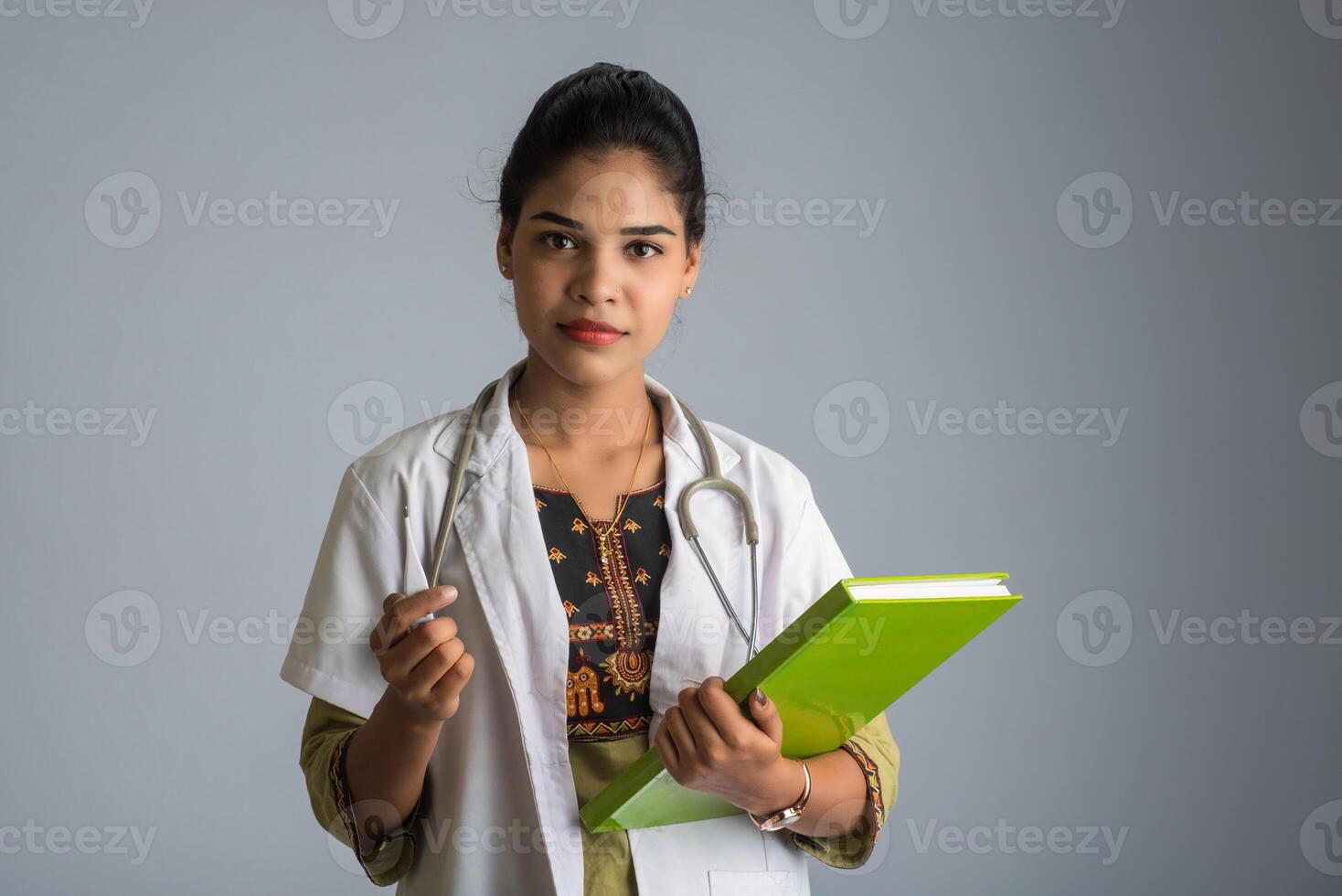 Beautiful young woman doctor with thermometer and report or book photo