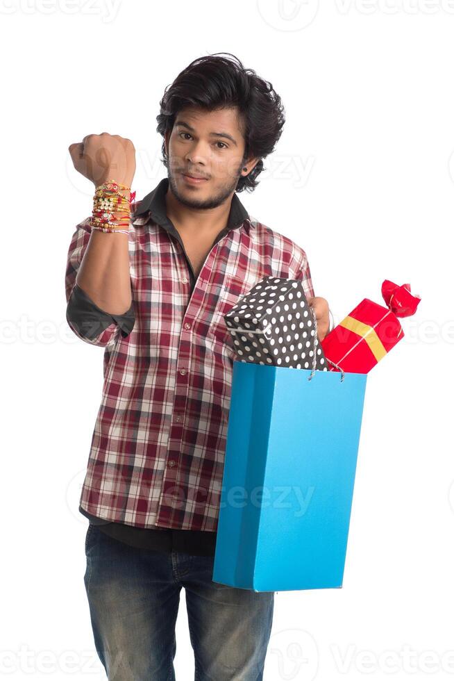 Young men showing rakhi on his hand with shopping bags and gift box on the occasion of Raksha Bandhan festival. photo