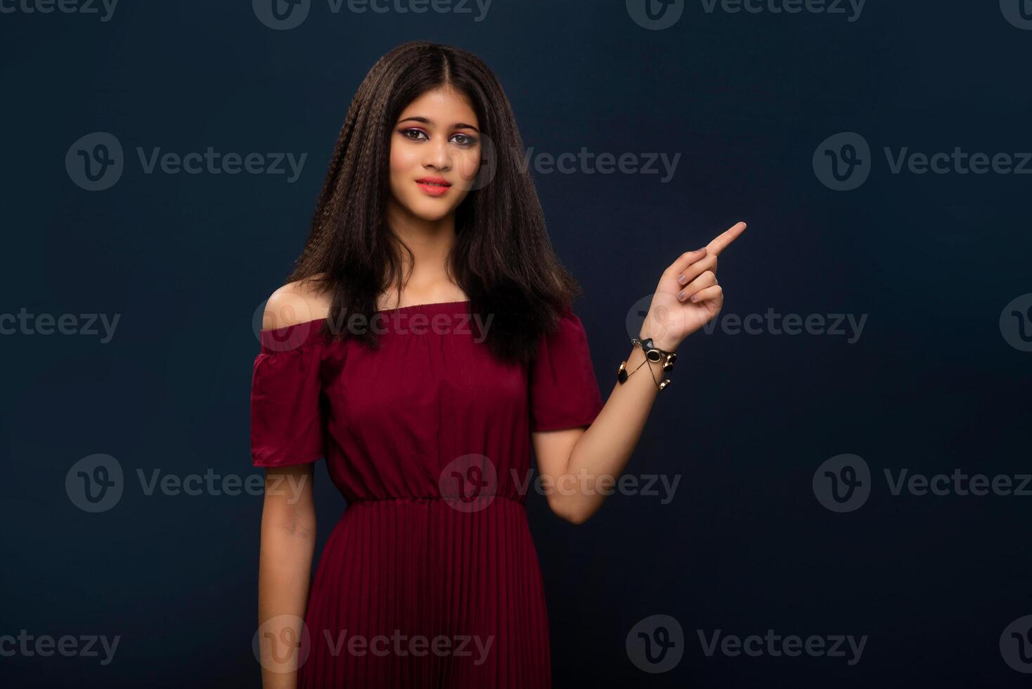 Portrait of a successful cheerful young girl pointing and presenting something with hand or finger with a happy smiling face. photo