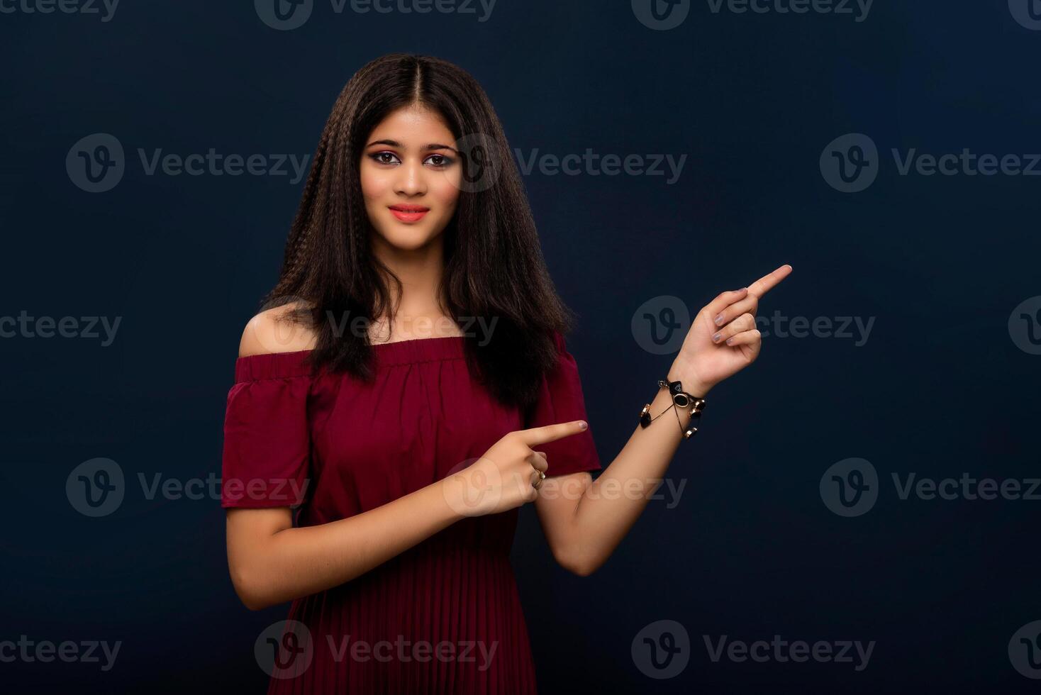 Portrait of a successful cheerful young girl pointing and presenting something with hand or finger with a happy smiling face. photo