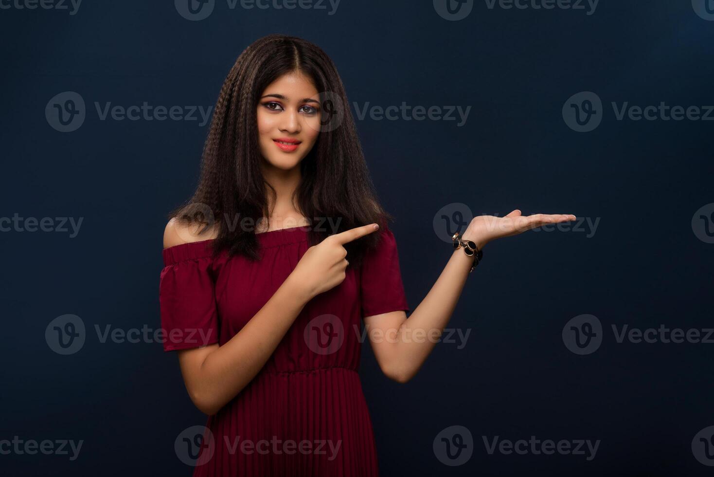 Portrait of beautiful young girl presenting something, showing copy space on her palm on a grey background photo