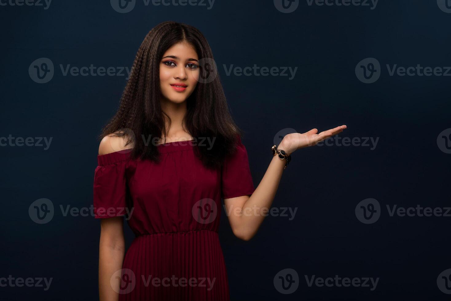 Portrait of beautiful young girl presenting something, showing copy space on her palm on a grey background photo