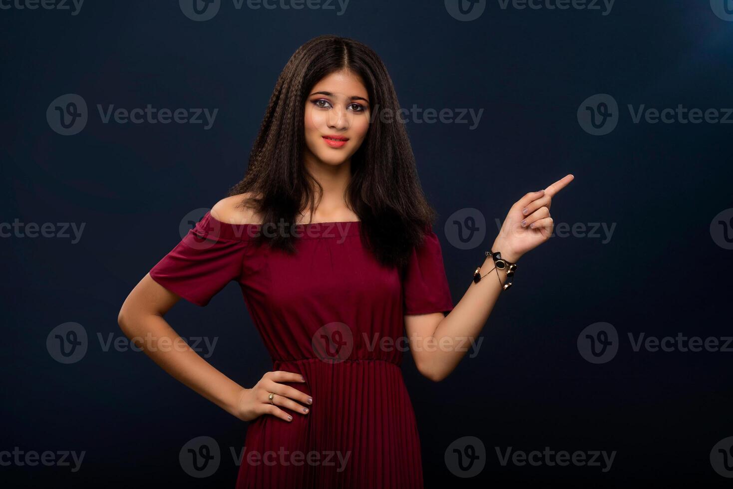 Portrait of a successful cheerful young girl pointing and presenting something with hand or finger with a happy smiling face. photo