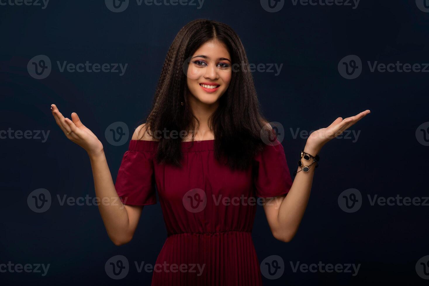 Portrait of beautiful young girl presenting something, showing copy space on her palm on a grey background photo