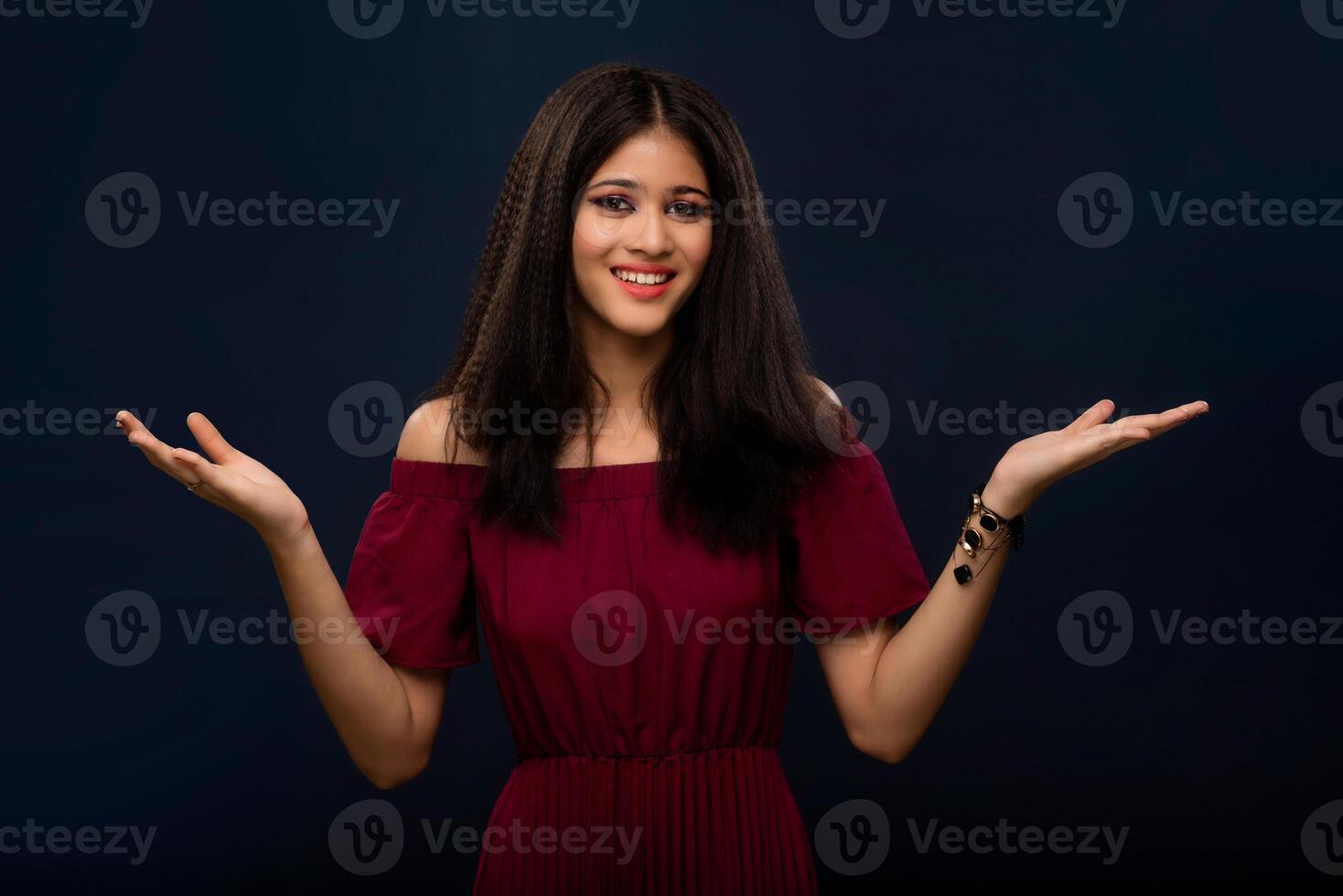 Portrait of beautiful young girl presenting something, showing copy space on her palm on a grey background photo